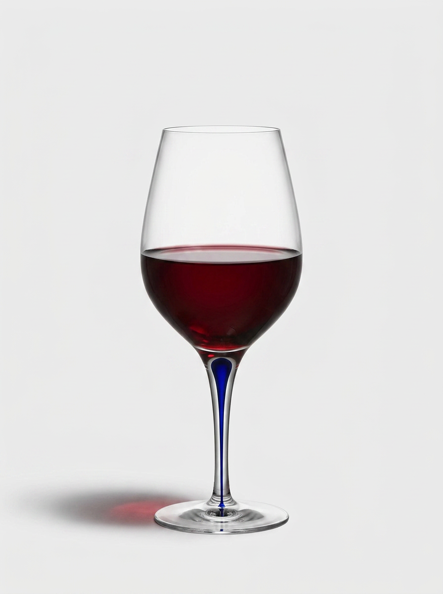 Rödvinsglas i Orrefors Intermezzo Blå-stil med en droppe kobolt i stjälken, fyllt med rubinrött vin.